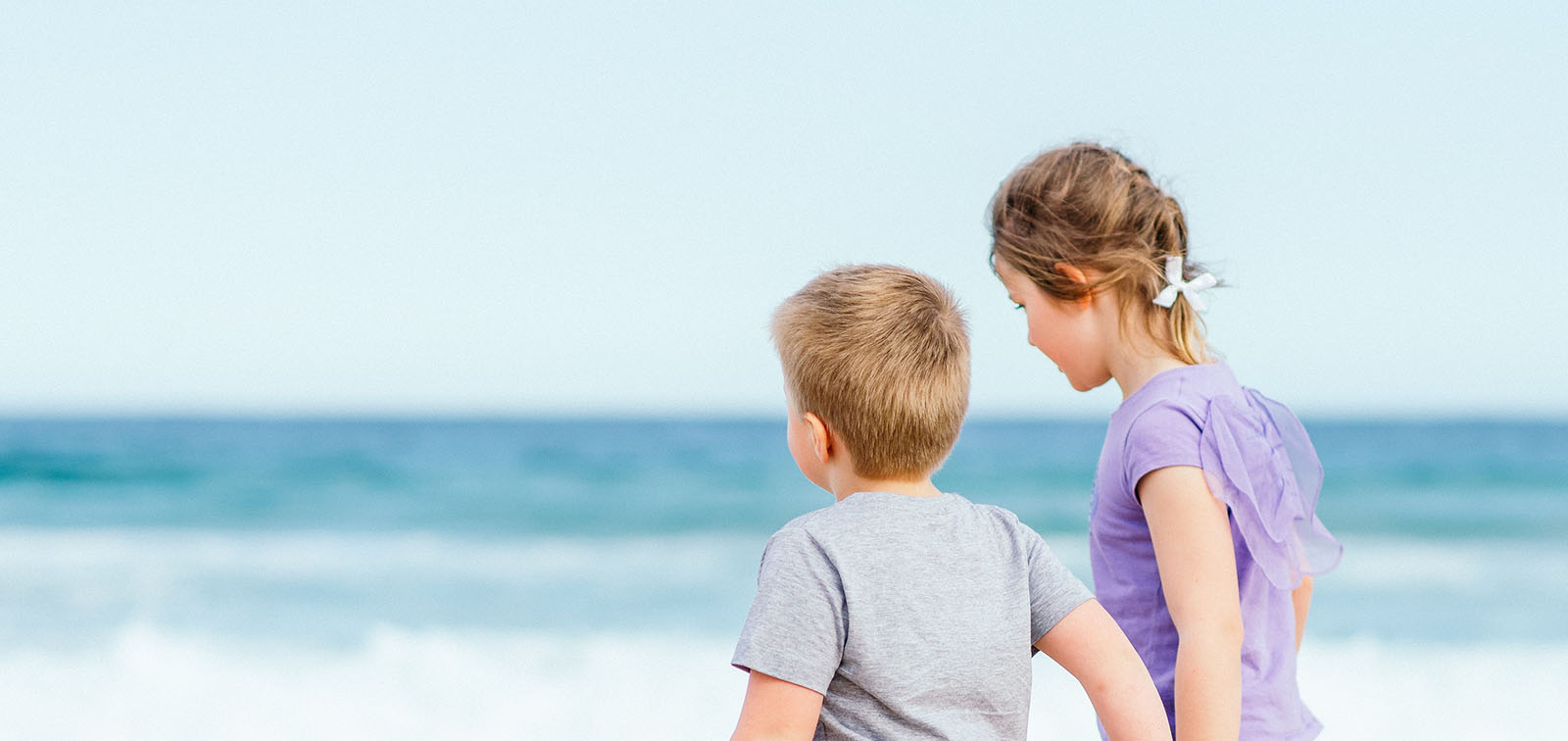 Two children walk along the beach